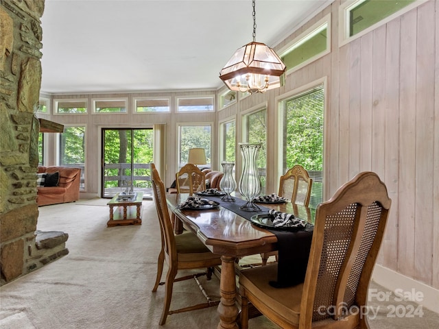 carpeted dining area featuring a notable chandelier and wood walls