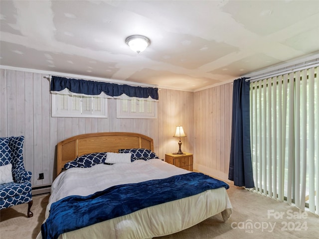 bedroom featuring a baseboard radiator, carpet flooring, wooden walls, and multiple windows