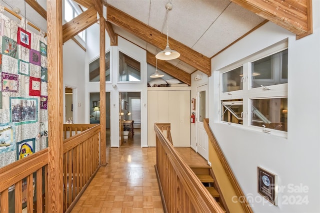 hall featuring beamed ceiling, light parquet floors, a textured ceiling, and high vaulted ceiling