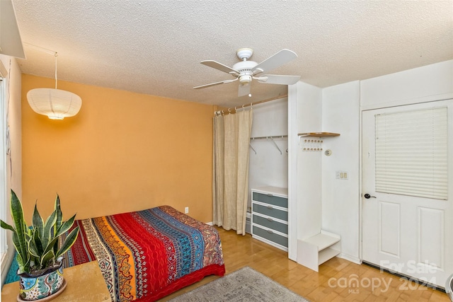 bedroom with a textured ceiling, ceiling fan, and light hardwood / wood-style floors