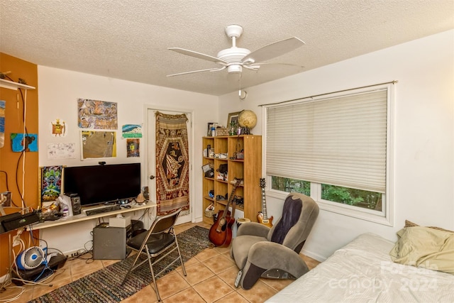 bedroom featuring light tile patterned floors, ceiling fan, and a textured ceiling