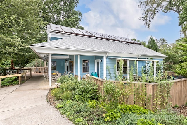 view of front of house featuring a fenced front yard, covered porch, and a shingled roof