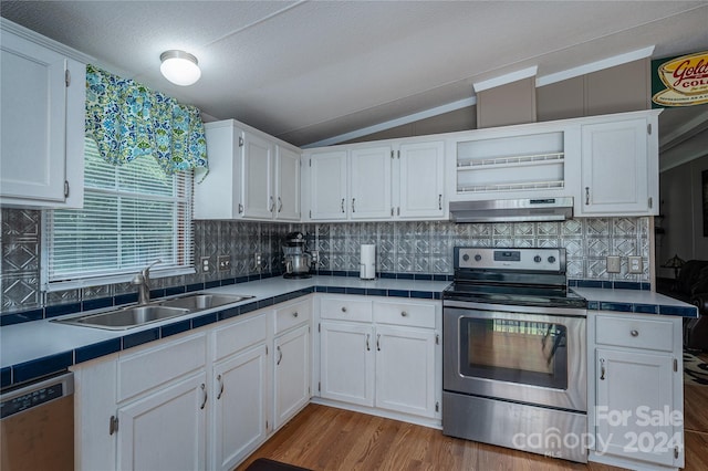 kitchen with white cabinets, appliances with stainless steel finishes, lofted ceiling, and tile countertops