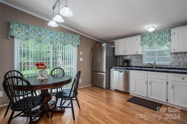 kitchen featuring stainless steel appliances, tile countertops, white cabinetry, and hanging light fixtures