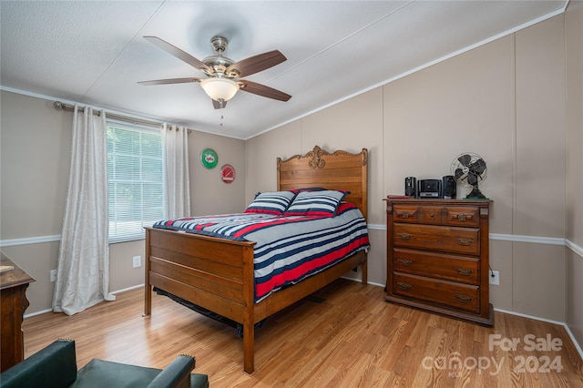 bedroom with ceiling fan, light hardwood / wood-style floors, a textured ceiling, and ornamental molding