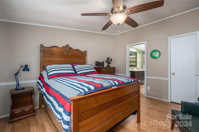 bedroom with ceiling fan, connected bathroom, wood-type flooring, and crown molding