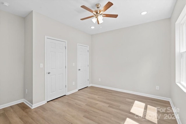 unfurnished bedroom with ceiling fan, light hardwood / wood-style floors, and two closets