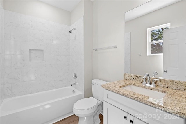 full bathroom featuring hardwood / wood-style floors, vanity, tiled shower / bath combo, and toilet