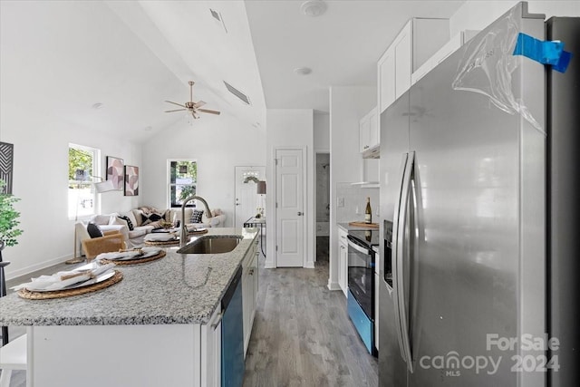 kitchen featuring lofted ceiling, white cabinetry, an island with sink, and appliances with stainless steel finishes