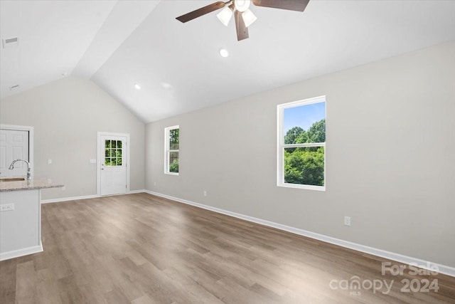 unfurnished living room with light wood-type flooring, plenty of natural light, and lofted ceiling