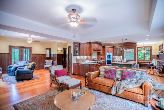 living room with ceiling fan, a wealth of natural light, light hardwood / wood-style flooring, and french doors