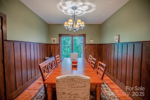 dining area with wood-type flooring and a notable chandelier