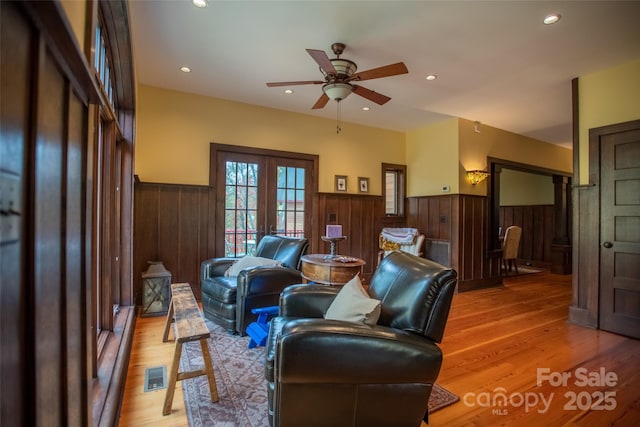 living room featuring ceiling fan, french doors, and light hardwood / wood-style floors