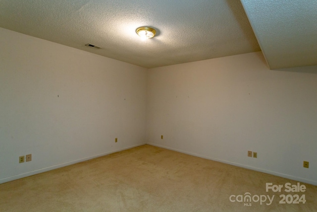 carpeted empty room featuring a textured ceiling