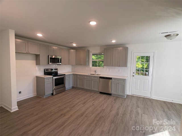 kitchen featuring hardwood / wood-style floors, gray cabinets, sink, and stainless steel appliances