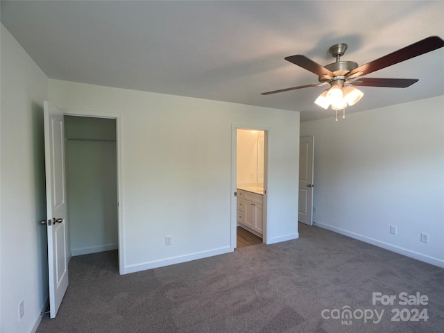 unfurnished bedroom with dark colored carpet, ceiling fan, and connected bathroom