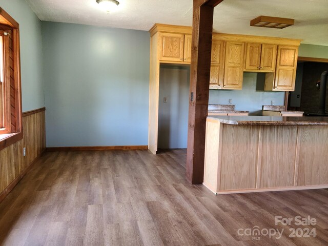 kitchen featuring light brown cabinets, wooden walls, and hardwood / wood-style floors