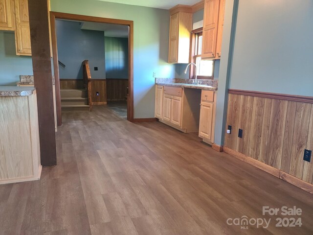 kitchen featuring light brown cabinets, sink, wood walls, and hardwood / wood-style flooring