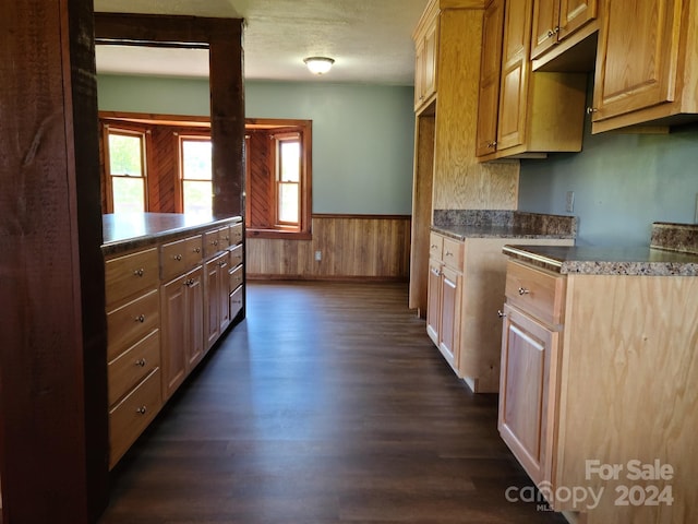 kitchen featuring a textured ceiling, dark hardwood / wood-style flooring, and wood walls