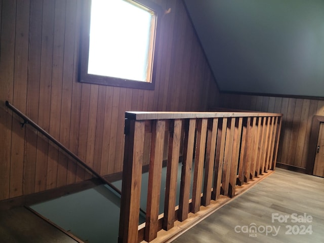 staircase featuring wooden walls and vaulted ceiling