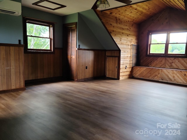 additional living space with an AC wall unit, wooden ceiling, a wealth of natural light, and wood walls