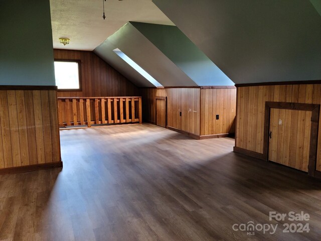 bonus room featuring lofted ceiling with skylight and dark hardwood / wood-style flooring