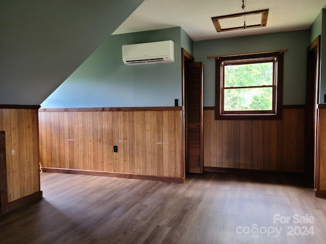 additional living space featuring a wall unit AC and dark hardwood / wood-style flooring