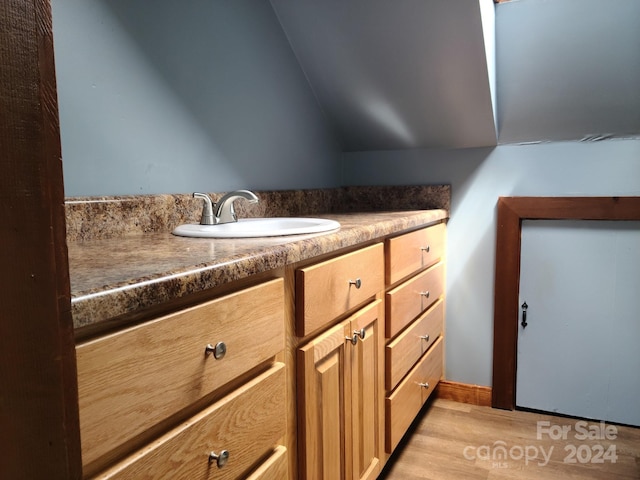 bathroom featuring wood-type flooring, vanity, and lofted ceiling