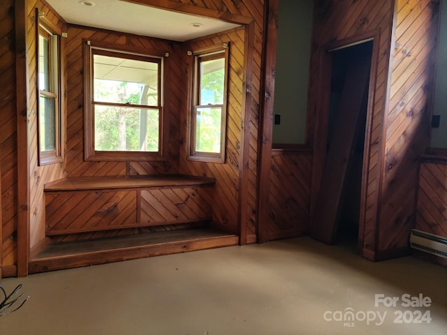 interior space with baseboard heating and wooden walls