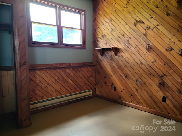 empty room with a baseboard heating unit and wood walls