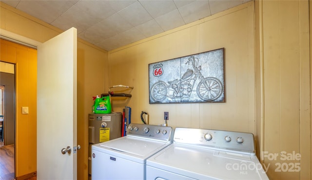 laundry area featuring washing machine and dryer, electric water heater, and wooden walls