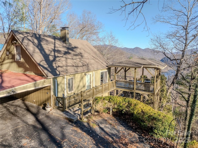 rear view of property with a carport and a deck with mountain view