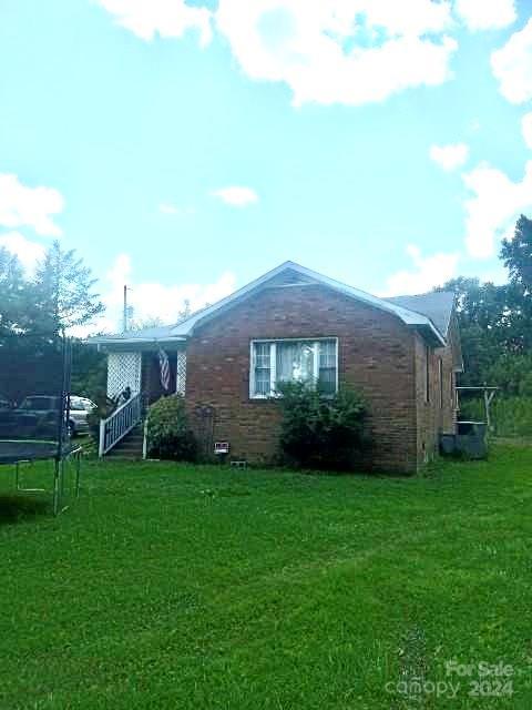 view of side of home featuring a trampoline and a yard