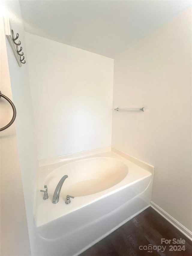 bathroom featuring hardwood / wood-style flooring and a tub to relax in