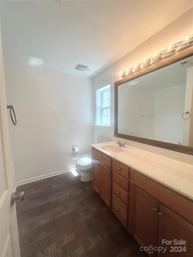 bathroom featuring toilet, hardwood / wood-style flooring, and vanity