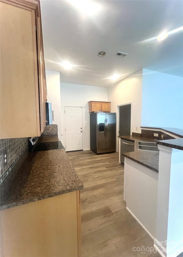 kitchen with stainless steel appliances, tasteful backsplash, sink, kitchen peninsula, and light wood-type flooring