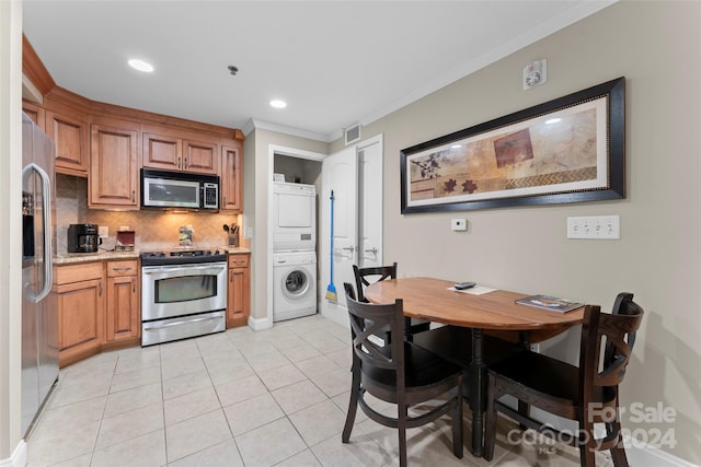 kitchen featuring ornamental molding, appliances with stainless steel finishes, tasteful backsplash, light tile patterned flooring, and stacked washer / dryer