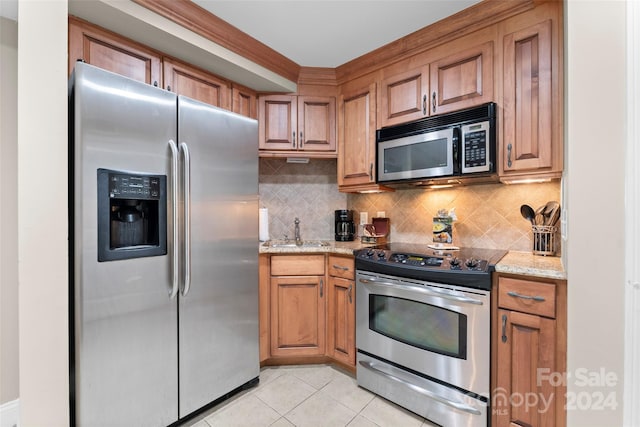 kitchen featuring sink, light tile patterned floors, tasteful backsplash, light stone counters, and stainless steel appliances