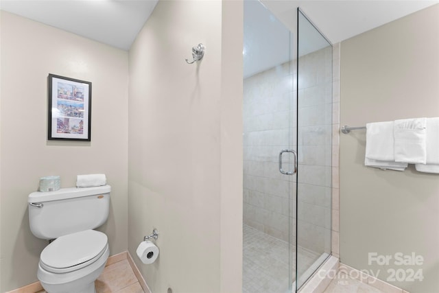 bathroom featuring tile patterned floors, a shower with shower door, and toilet