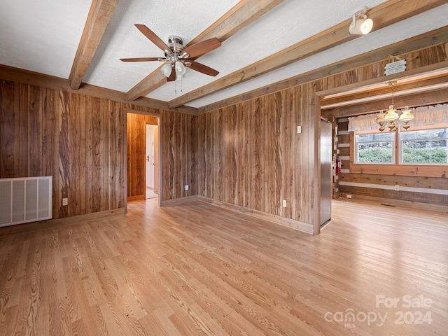 unfurnished living room featuring ceiling fan, wood walls, beam ceiling, and light hardwood / wood-style flooring