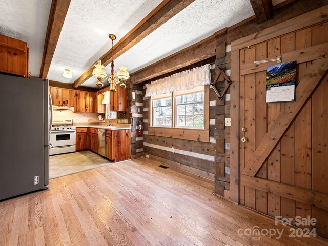 kitchen featuring beamed ceiling, stainless steel appliances, light wood-type flooring, a textured ceiling, and wooden walls