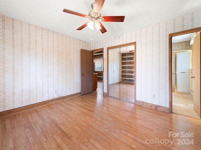 unfurnished bedroom featuring connected bathroom, ceiling fan, and light wood-type flooring