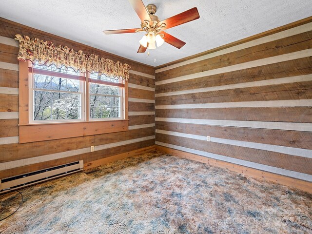 carpeted spare room featuring ceiling fan, wood walls, a textured ceiling, and a baseboard heating unit