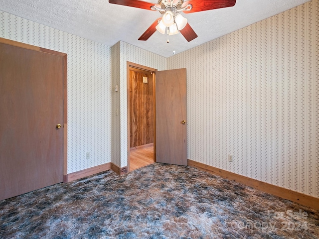 carpeted spare room with ceiling fan and a textured ceiling