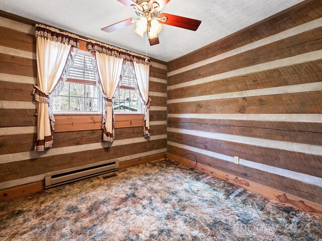 carpeted empty room with a baseboard heating unit, a textured ceiling, ceiling fan, and wood walls