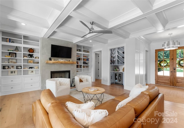 living room with light wood-type flooring, beam ceiling, a large fireplace, and built in features