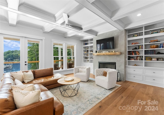 living room featuring french doors, built in features, beamed ceiling, light hardwood / wood-style floors, and a fireplace