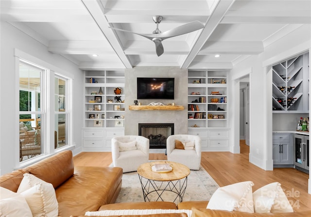 living room featuring a large fireplace, wine cooler, built in features, and light hardwood / wood-style floors