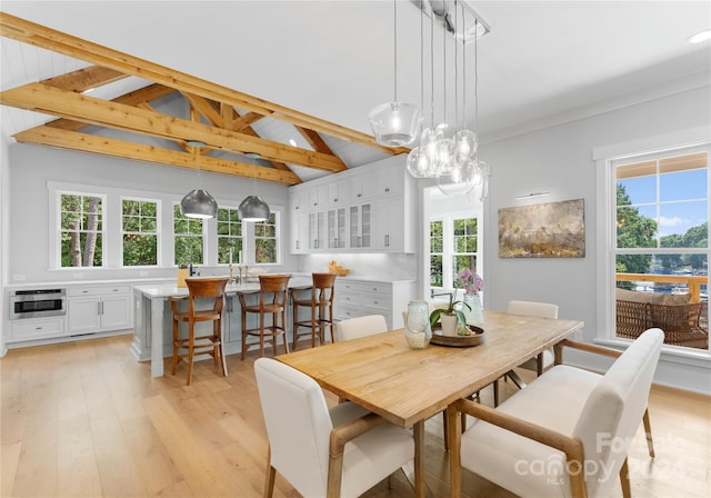 dining area with light hardwood / wood-style flooring, beamed ceiling, and high vaulted ceiling