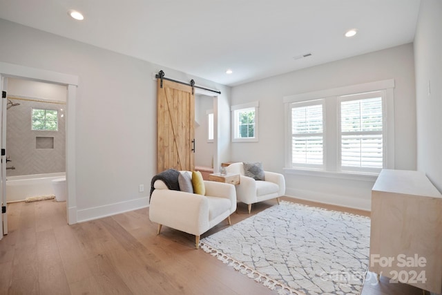 sitting room with a barn door and light wood-type flooring